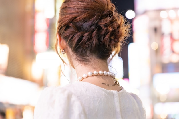 Japanische Frau mit glamouröser Halskette in den Straßen von Tokio, Japan. Rückansicht