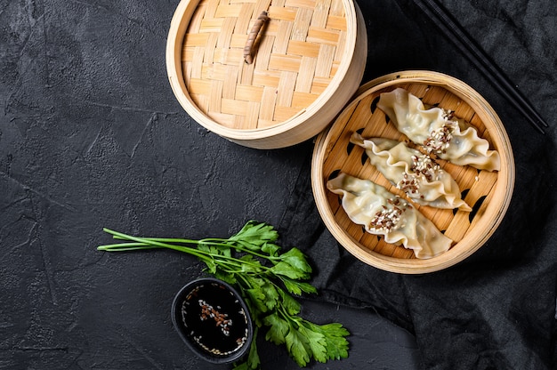 Japanische Gyoza in einem traditionellen Bambusdampfer. Draufsicht. Platz für Text. rustikaler alter Vintage schwarzer Hintergrund