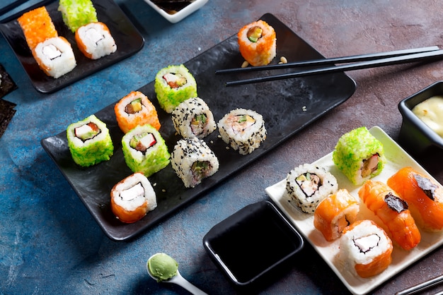 Japanische Lebensmittelsushi, Rollen, Essstäbchen, Sojasoße auf Steinhintergrund