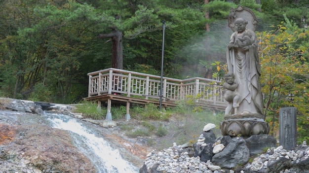 Japanische Mönchskulpturstatue unter natürlichem grünem Wald an der heißen Quelle onsen kusatsu Stadt