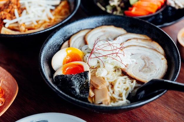 Japanische Nudel in Miso-Suppe mit Chashu-Schweinefleisch, gekochtes Ei, trockene Meerespflanze.