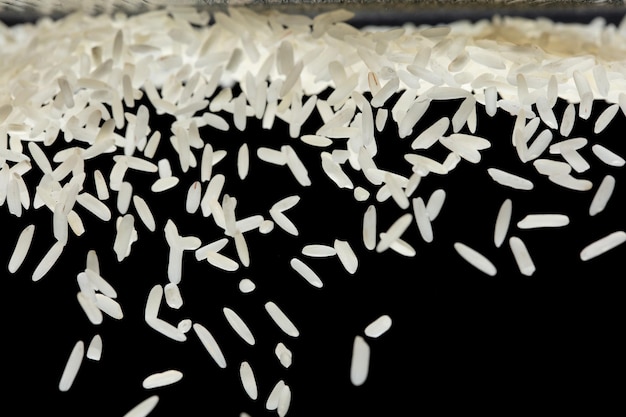 Japanische Reis fliegende Explosion weiße Körner Reisen fallen abstrakte Fliege Schöne vollständige Samen Jasmin Reis Spritz in der Luft Lebensmittel Objekt Design Schwarzer Hintergrund isoliert selektiver Fokus verschwommen
