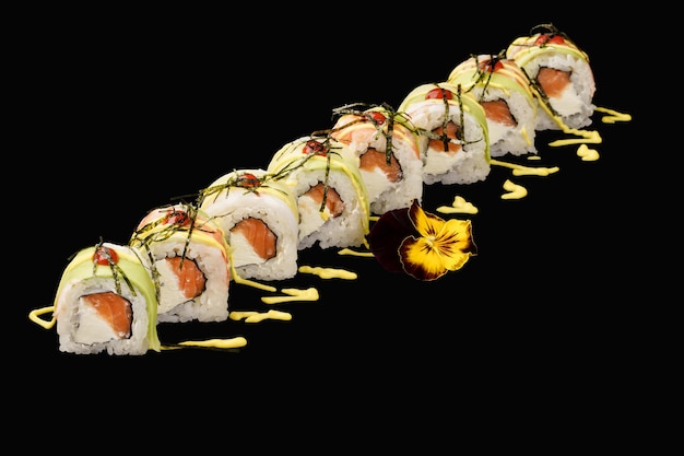 Japanische Sushi-Rolle mit Tiger Shrimp Lachs Philadelphia-Käse Avocado Japanische Mayonnaise Sriracha-Sauce isoliert auf schwarzem Hintergrund