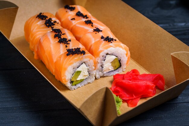 Japanische traditionelle Rolle mit Lachs Sushi-Lieferservice Sushi-Rollen im Karton auf dunklem Hintergrund