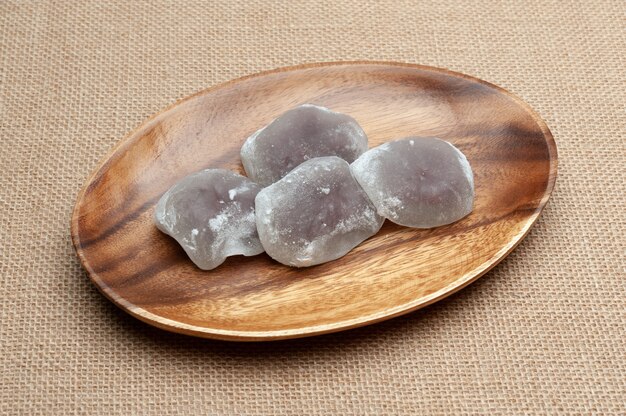 Japanische traditionelle Süßigkeit namens Daifuku Mochi auf Holzplatte isoliert auf Jute-Hintergrund