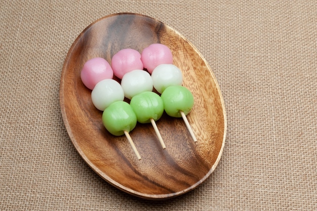 Japanische traditionelle Süßigkeit namens Dango Mochi auf Holzplatte isoliert auf Jute-Hintergrund