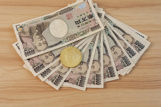 Japanische Yen-Banknote mit goldener Dogecoin-Kryptowährung auf dem Tisch Japan-Bargeld Steuerrezession Wirtschaft Inflation Kryptoinvestition und dezentrale Finanzkonzepte