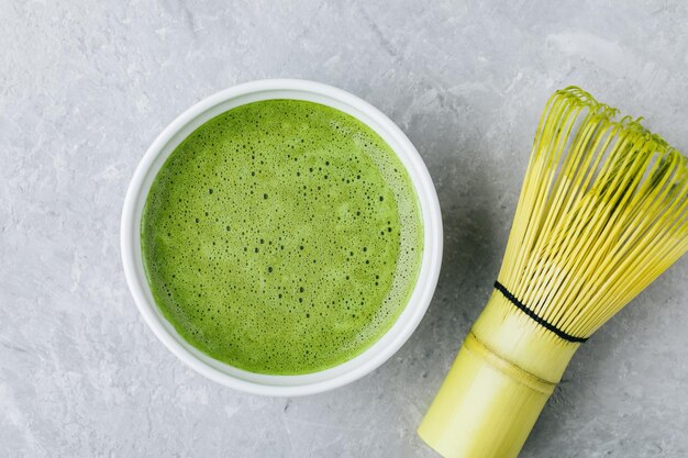 Japanischer Matcha-Grüntee-Latte in weißer Schüssel auf grauem Steinhintergrund Draufsicht