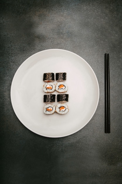 japanischer Sushi-Reisbrötchenlachs und -käse, der oben auf weißer Platte präsentiert wird