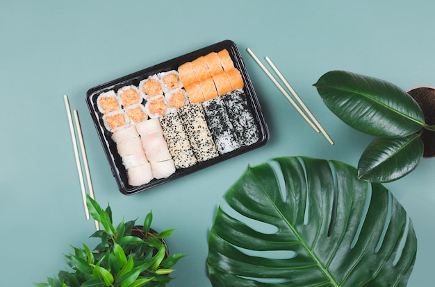 Foto japanisches essen catering. sushi mit stäbchen, an der grünen oberfläche zum mitnehmen