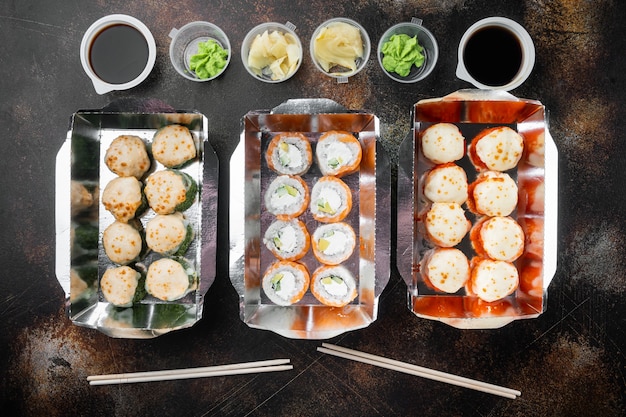 Japanisches Essenskonzept. Catering, verschiedene Arten von Sushi-Philadelphia-Brötchen und gebackene Garnelenbrötchen, auf altem dunklem rustikalem Hintergrund, Draufsicht flach