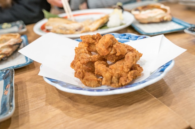 Japanisches Karaage-Huhn, gebraten in weißer Schale auf Papier und auf Holztisch gelegt