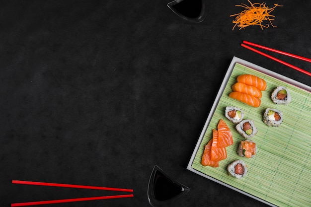 Japanisches Lebensmittel der frischen und köstlichen Sushi mit Essstäbchen auf schwarzem Hintergrund