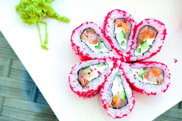 Japanisches Lebensmittel der Sushirolle im Restaurant. roter Rogen des fliegenden Fisches. Sushi nah oben auf weißer Platte.