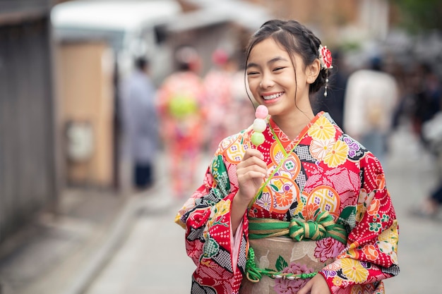 Japanisches Mädchen im traditionellen Kimono-Kleid genießt Reisen und Essen in der Yasaga-Straße in Kyoto, Japan