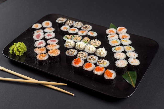 Japanisches Sushi-Rollen-Set serviert auf schwarzem Teller auf dunklem Hintergrund