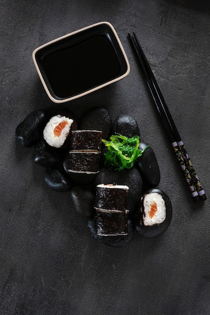 Japanisches Sushi serviert auf schwarzen Steinen. Ansicht von oben, Nahaufnahme auf dunklem Hintergrund.