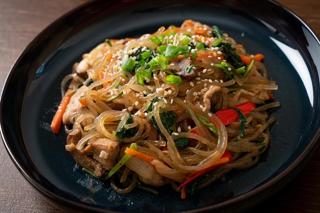 japchae o fideos de fideos coreanos salteados con verduras y carne de cerdo cubiertos con sésamo blanco - estilo de comida tradicional coreana