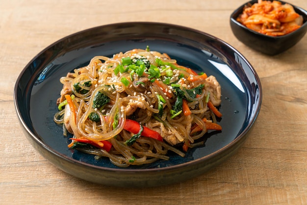 japchae o fideos de fideos coreanos salteados con verduras y carne de cerdo cubiertos con sésamo blanco - estilo de comida tradicional coreana