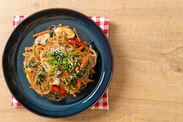 japchae o fideos de fideos coreanos salteados con verduras y carne de cerdo cubiertos con sésamo blanco - estilo de comida tradicional coreana