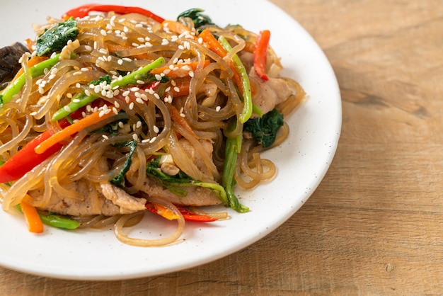 japchae o fideos de fideos coreanos salteados con verduras y carne de cerdo cubiertos con sésamo blanco - estilo de comida tradicional coreana