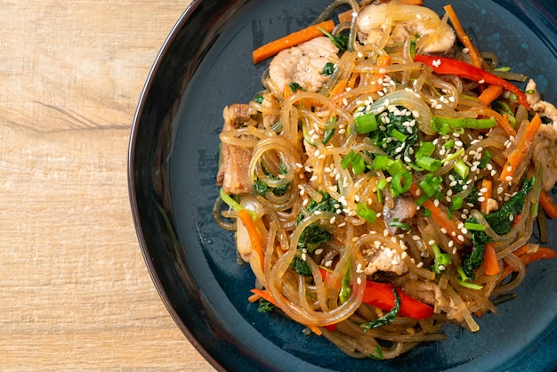 japchae o fideos de fideos coreanos salteados con verduras y carne de cerdo cubiertos con sésamo blanco - estilo de comida tradicional coreana