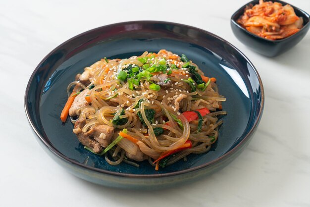 Japchae o fideos vermicelli coreanos salteados con verduras y cerdo cubiertos con sésamo blanco - estilo de comida tradicional coreana