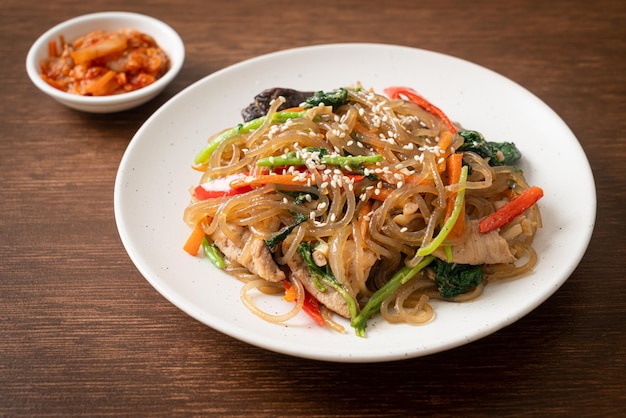 Japchae o fideos vermicelli coreanos salteados con verduras y cerdo cubiertos con sésamo blanco - estilo de comida tradicional coreana