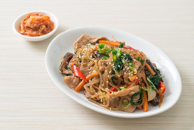 Japchae oder gebratene koreanische Fadennudeln mit Gemüse und Schweinefleisch, garniert mit weißem Sesam - traditionelle koreanische Küche