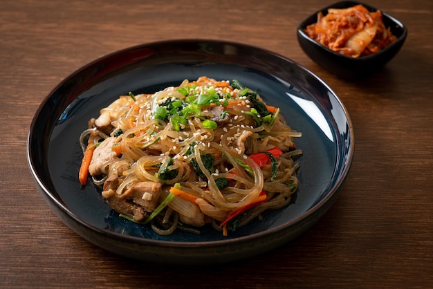 Japchae oder gebratene koreanische Fadennudeln mit Gemüse und Schweinefleisch, garniert mit weißem Sesam - traditionelle koreanische Küche