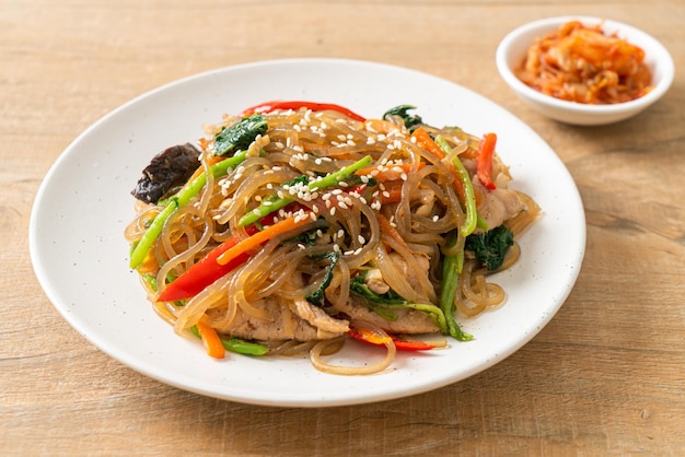 Japchae oder gebratene koreanische Fadennudeln mit Gemüse und Schweinefleisch, garniert mit weißem Sesam