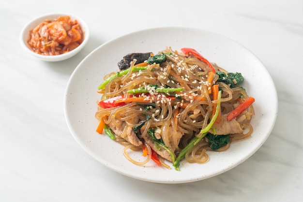 Japchae oder geröstete koreanische Vermicelli-Nudeln mit Gemüse und Schweinefleisch mit weißem Sesam