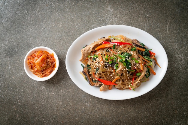 Japchae ou macarrão aletria coreano frito com legumes e carne de porco coberto com gergelim branco - estilo de comida tradicional coreana