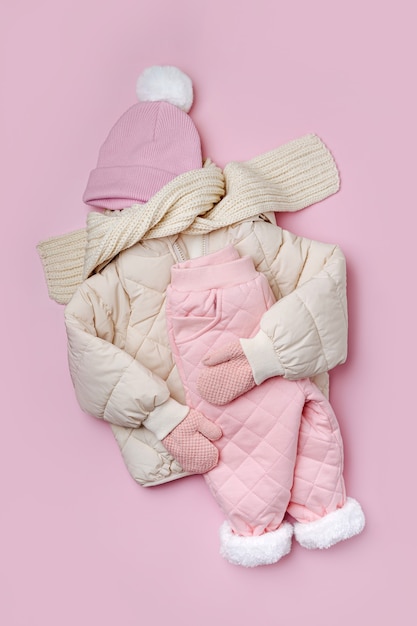 Jaqueta baiacu, calças quentes, chapéu e lenço em fundo rosa. conjunto de roupas de bebê para o inverno. roupa de moda infantil.