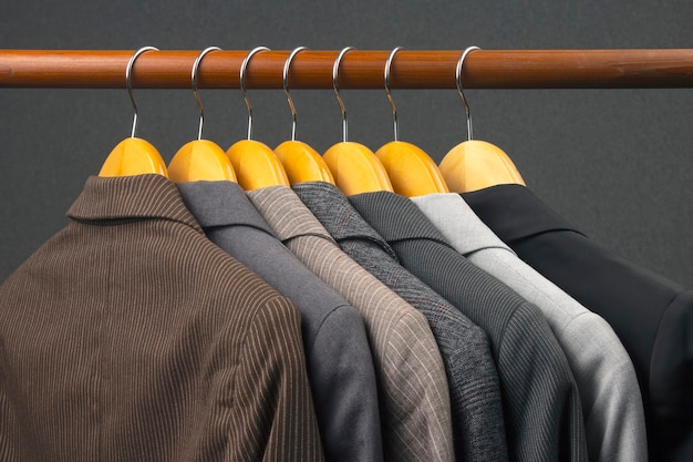 Jaquetas clássicas de escritório para mulheres diferentes estão penduradas em um cabide para guardar roupas. a escolha do estilo de roupas da moda.