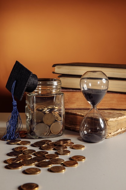 Jar com chapéu de formatura de moedas e economia de ampulheta e tema de educação