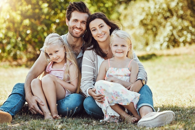 Jardín familiar y retrato de padres, hijos y gente feliz en el césped del parque bajo el sol Los niños, mamá y papá, sonríen con amor en las vacaciones de la naturaleza y las vacaciones de verano para relajarse en el césped del parque con paz