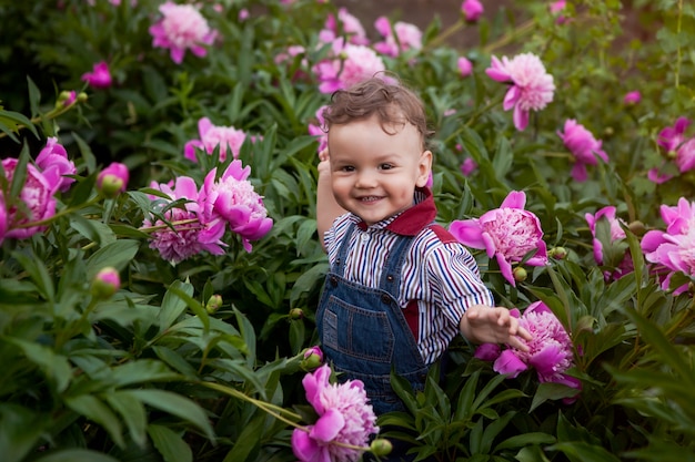 Jardín infantil en peonías rosas, un regalo para mamá recoge un ramo de flores.