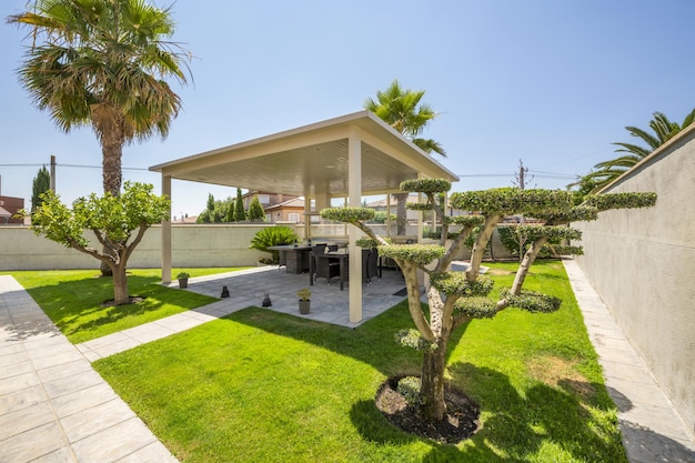 Jardín con mirador con mesas y sillas de mimbre y árboles artísticamente podados