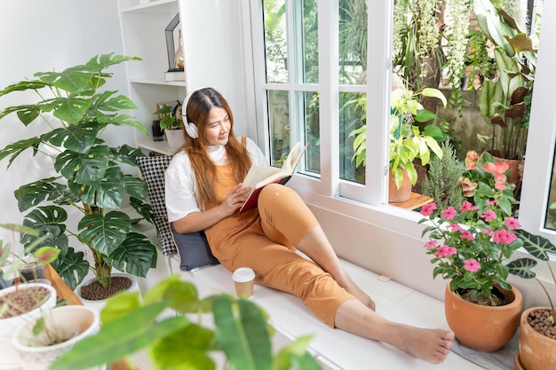 Jardinagem em casa e plantio de árvores no jardim botânico. Mulher asiática lendo livro e relaxe na temporada de primavera.