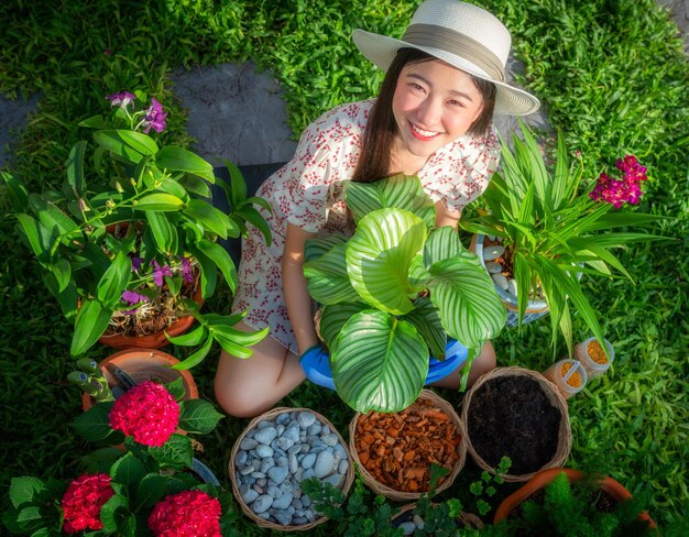 Foto jardineira asiática relaxa no jardim de sua casa com vaso de flores e ferramenta de material de jardineiro com fundo verde