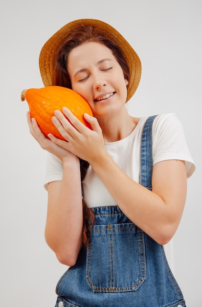 Jardineira em um macacão jeans com uma abóbora laranja madura conceito de vegetarianismo