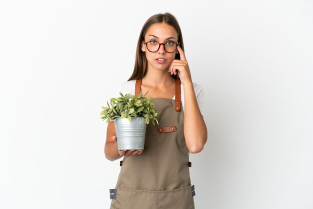 Jardineira segurando uma planta sobre um fundo branco isolado pensando em uma ideia