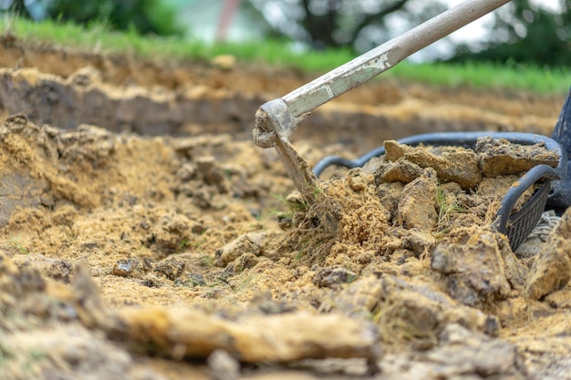 Jardineiro cava o solo com seu equipamento de jardinagem e prepara o terreno para o plantio.