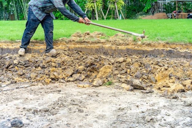 Jardineiro cava o solo com seu equipamento de jardinagem e prepara o terreno para o plantio.