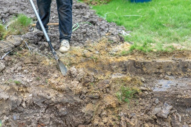 Jardineiro cava o solo com seu equipamento de jardinagem e prepara o terreno para o plantio.