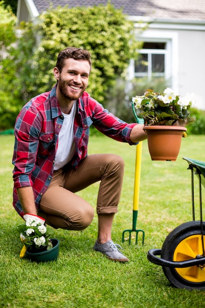 Foto jardineiro feliz segurando vasos de plantas no quintal