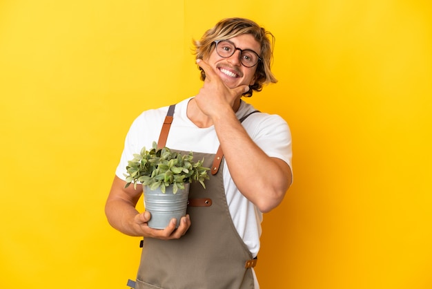 Jardineiro loiro segurando uma planta isolada