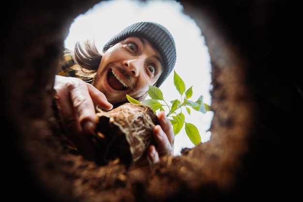 Jardineiro masculino animado plantando vista de flores do buraco de baixo para cima olhando para a câmera de alta qualidade