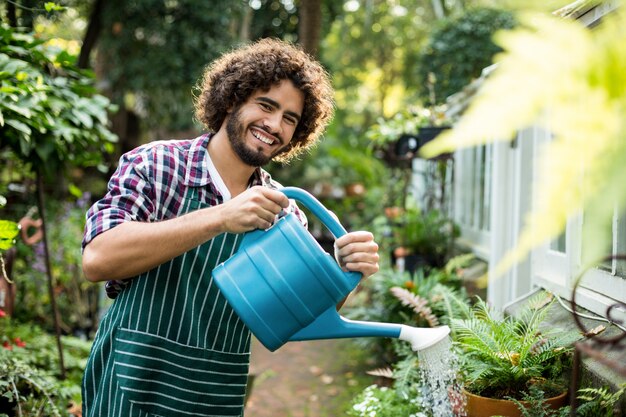 Jardineiro masculino confiante que molha plantas em vaso